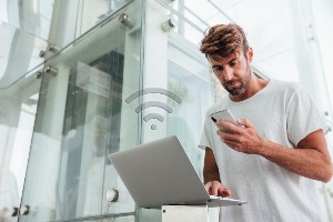 Man using a laptop whilst on his phone