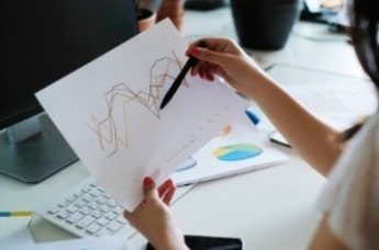 Woman looking at piece of paper showing a graph 