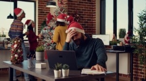 Man with christmas hat on but looking frustrated at work