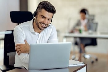 Man with headset on smiling at laptop