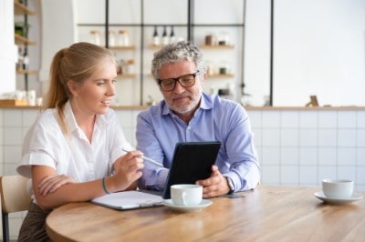 Man and women sat at table looking at screen